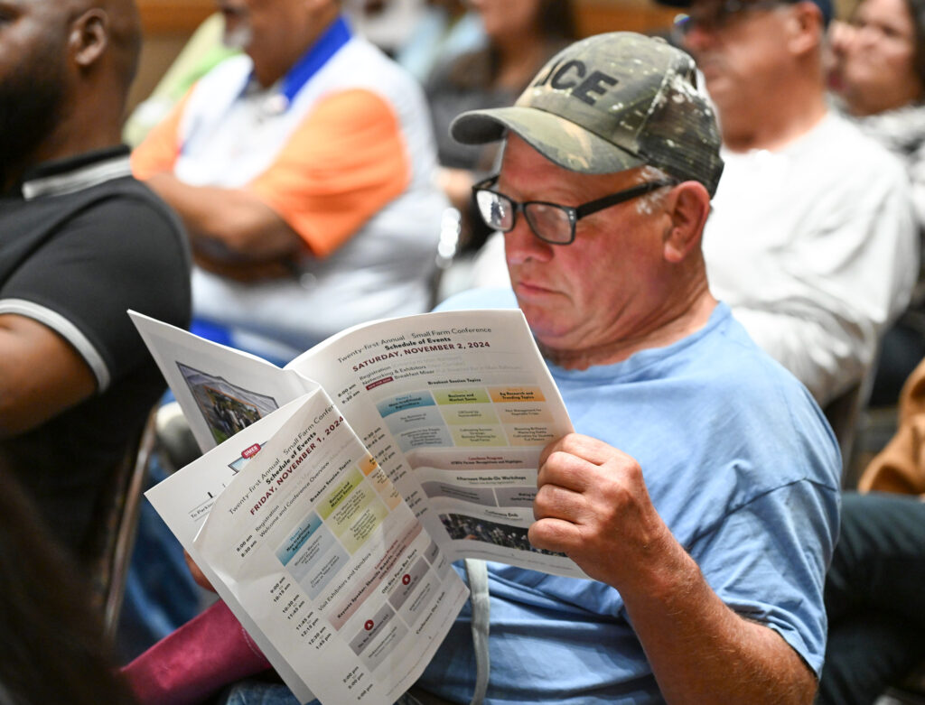An attendee looks through the 21st Small Farm Conference program.