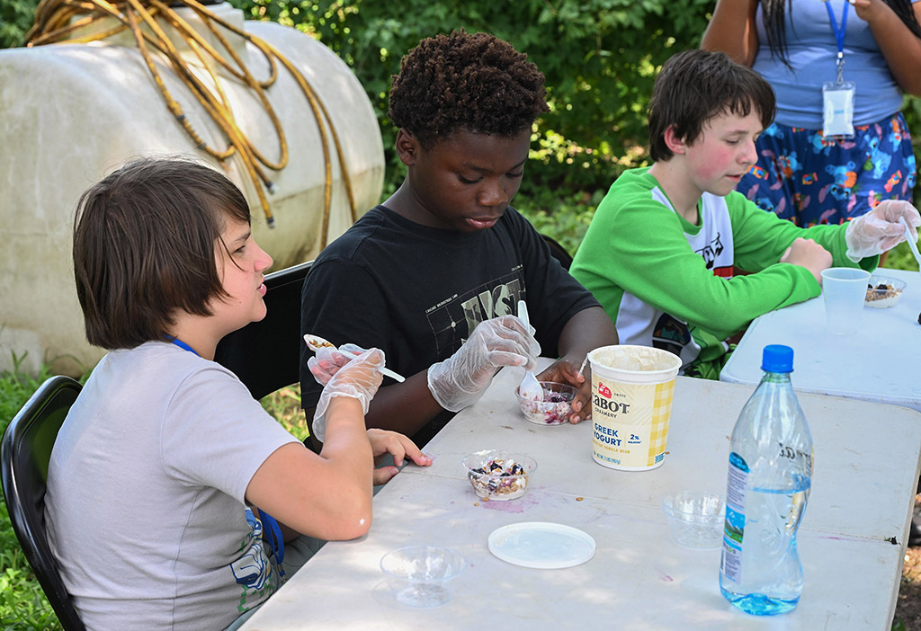 Weston Phillips, Kyle Warner and Gabe Hill sample a nutritional snack made of fruit and yogurt.