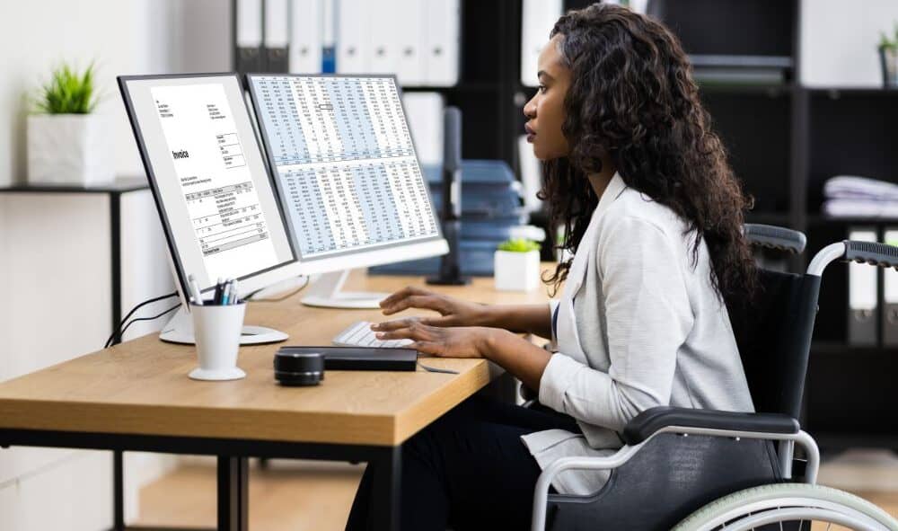 B.S. in Rehabilitation Services—wheelchair user working at a computer with accessibility and work supports.