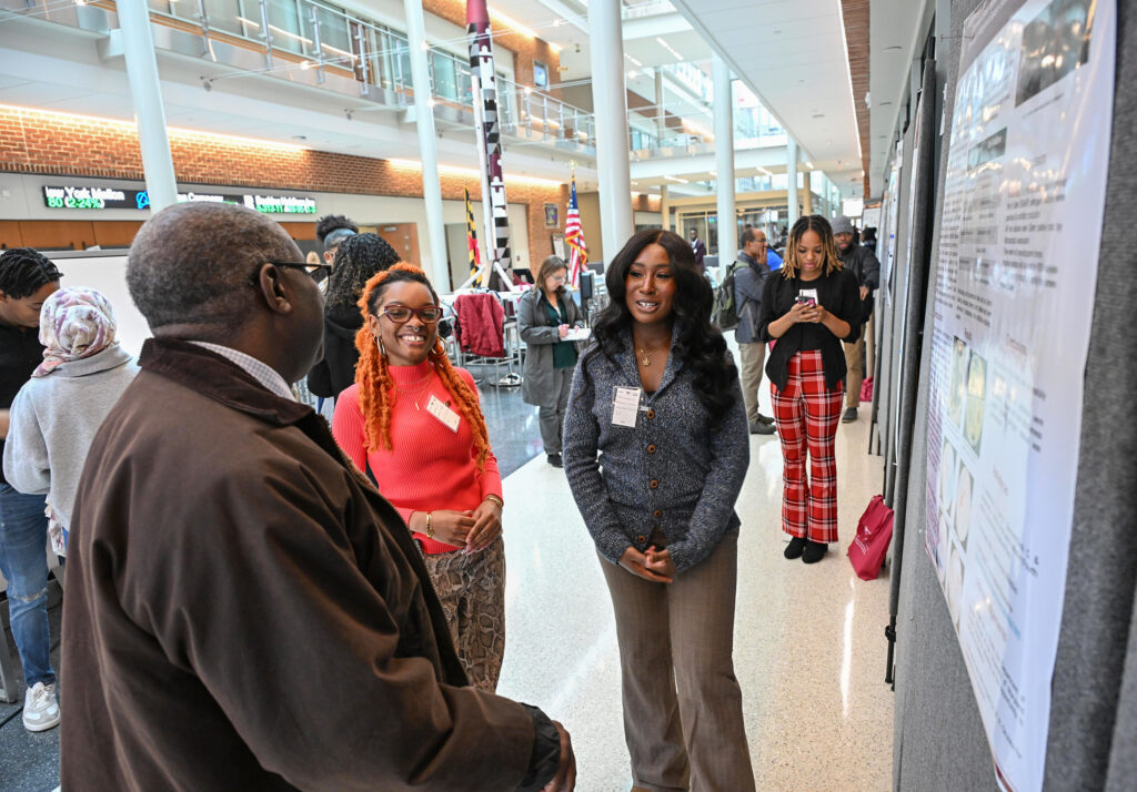 Student talks about her poster at Student-led Undergraduate Research Symposium in 2024.