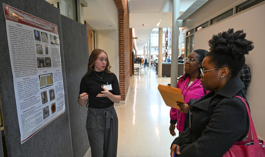 Student talks about her poster at Student-led Undergraduate Research Symposium in 2024.