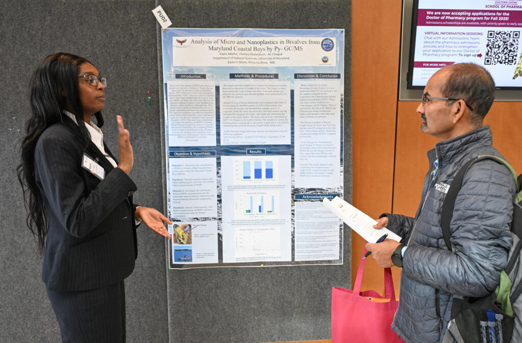 Student talks about her poster at Student-led Undergraduate Research Symposium in 2024.