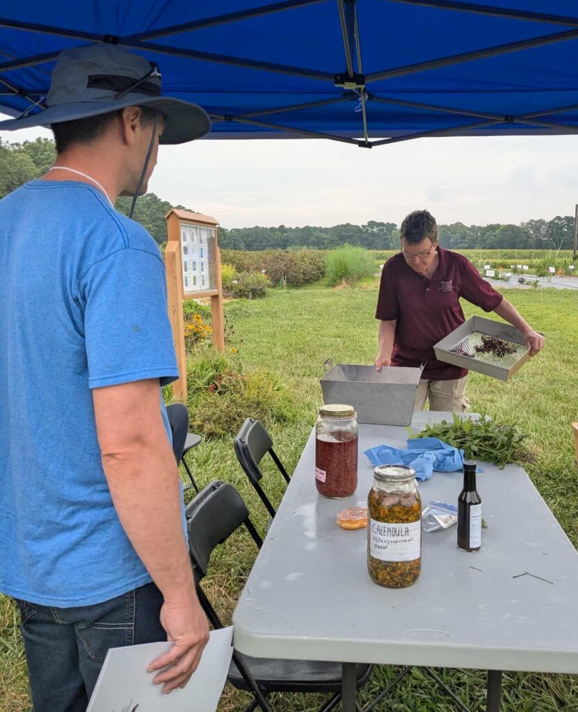 A workshop participant watches a UMES Extension specialty herbalist demonstrate herb harvesting.