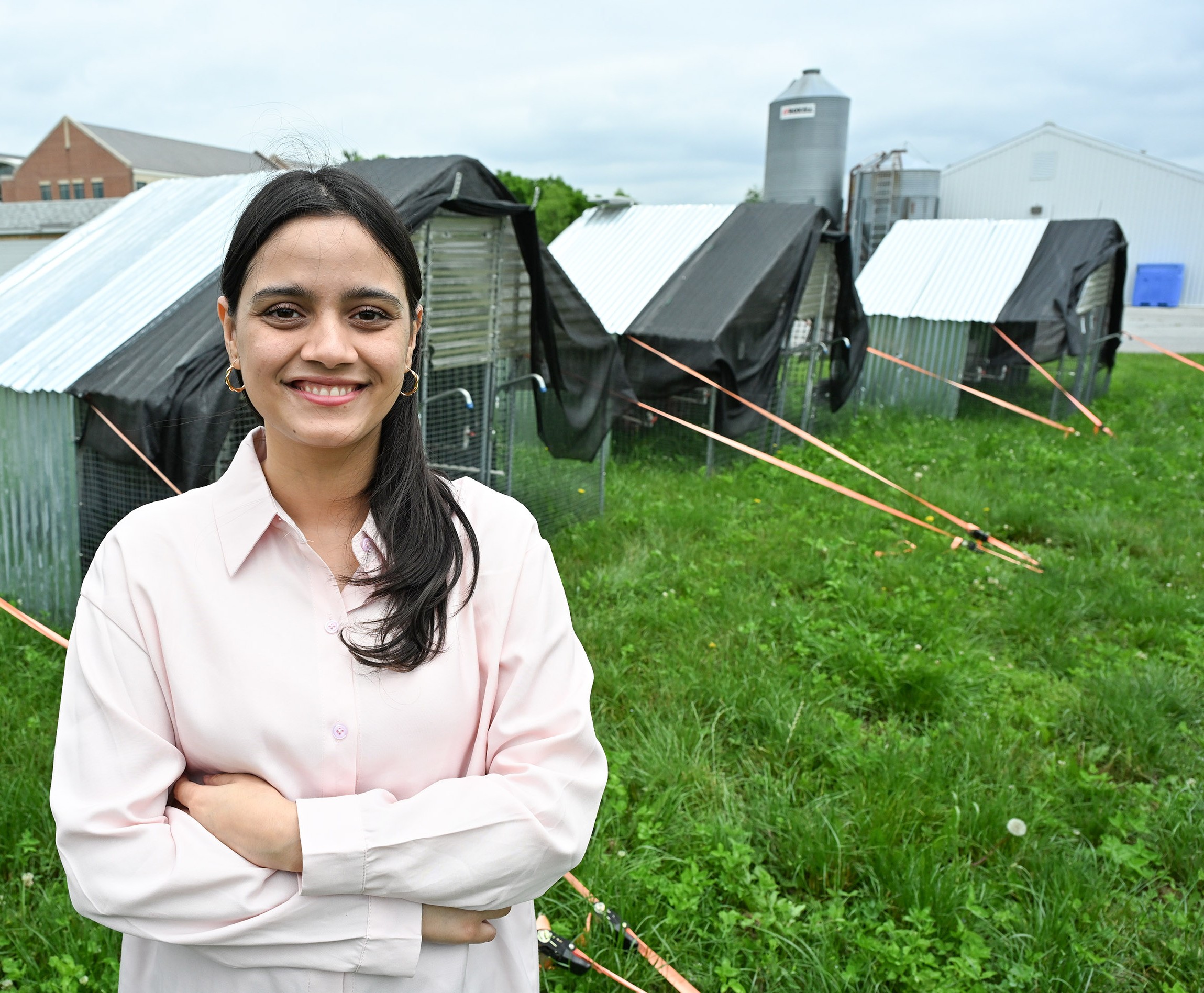 UMES graduate research assistant Unishma Ghimire is pictured by moveable pasture-raised poultry houses.