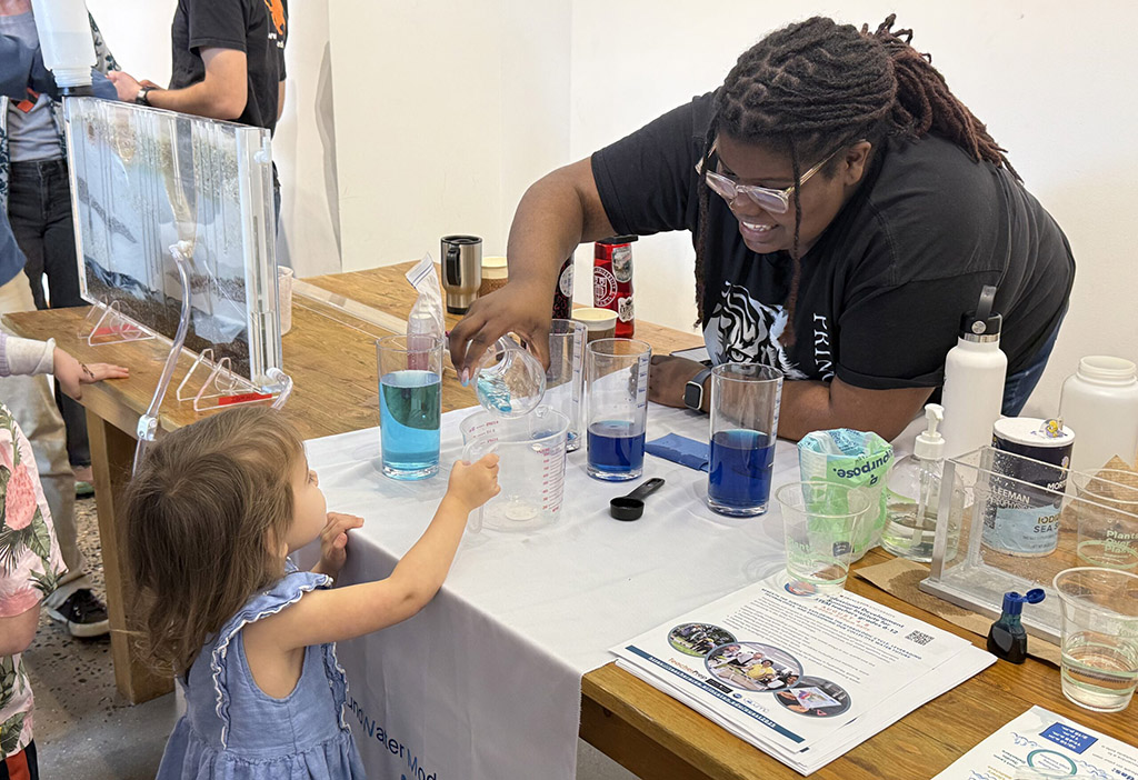 UMES alumna Jasmine Pinchinat now working at Princeton helps a child with an experiment during Princeton World Water Day education and outreach event.