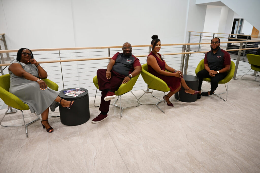 Two black women and two black men sitting in green chairs.